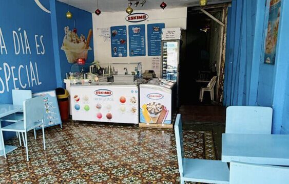 Interior of the Eskimo Ice Cream shop in San Juan del Sur with bright sign and beachgoers passing by.