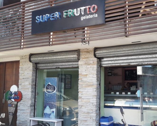 A colorful display of various gelato flavors at Gelateria SUPERFRUTTO in San Juan del Sur, with customers enjoying their treats outside