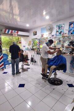 Barber inside Barbería 365 in San Juan del Sur giving a fresh haircut in a clean, modern shop with mirrors and tools in view