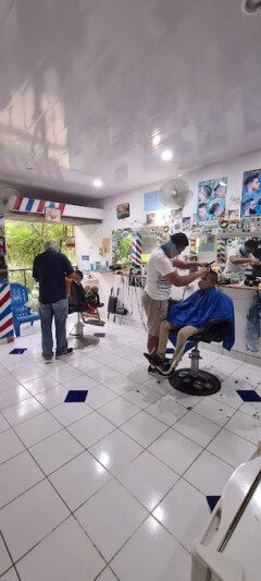 Barber inside Barbería 365 in San Juan del Sur giving a fresh haircut in a clean, modern shop with mirrors and tools in view