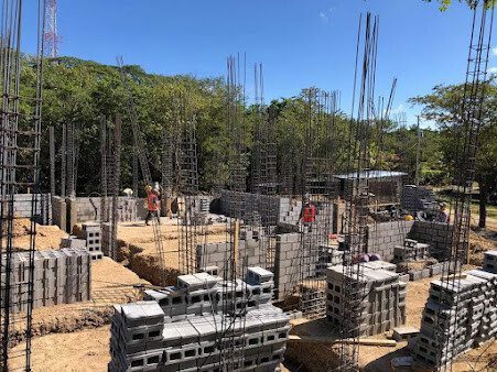 Construction crew from Construcciones Fuentes S.A. working on a residential building site near San Juan del Sur with tools and structural frames visible