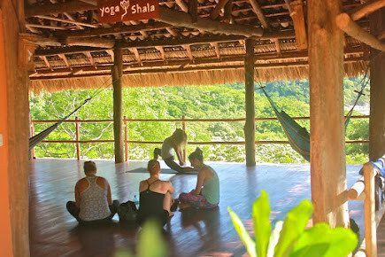 "Ocean-view yoga deck at Costa Dulce Retreat in San Juan del Sur, Nicaragua, surrounded by lush jungle with guests practicing yoga under a thatched roof."