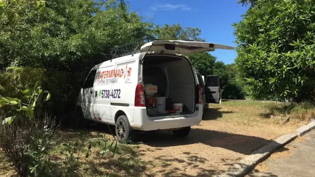 A pest control technician from Exterminador Control de Plagas San Juan Del Sur wearing protective gear and spraying insecticide in a residential interior