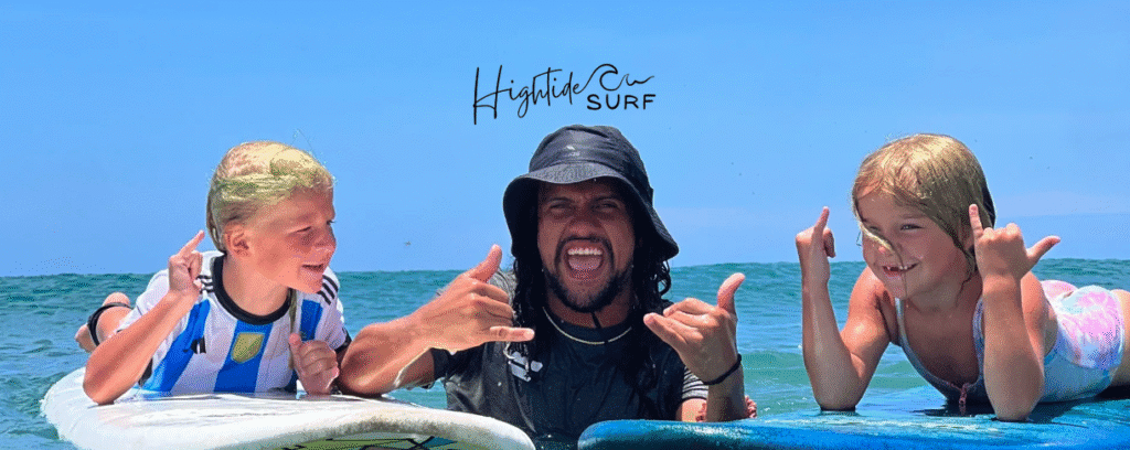 Hightide Surf School image of surf instructor with kids he's teaching on the waves
