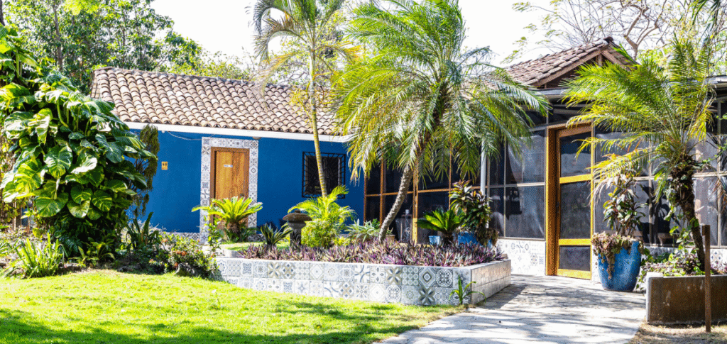Beachfront view of Xalli Ometepe Beach Hotel with garden, lake, and volcanoes in background